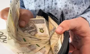 Dłonie trzymające portfel z polskimi banknotami 200 zł.