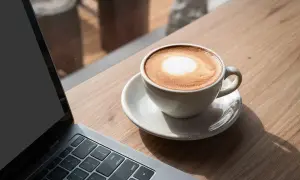Kawa latte obok laptopa. Idealna przerwa na 8 godzin pracy, by naładować baterie.