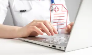 Lekarz wpisuje dane pacjenta na laptopie, dbając o zgodność z oryginałem dokumentacji medycznej.