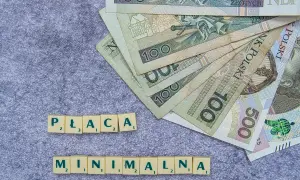 Płaca minimalna w Polsce to temat dyskusji. Na zdjęciu polskie banknoty i litery tworzące hasło.