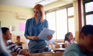 Nauczycielka z dokumentami rozmawia z uczniem w klasie.