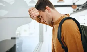 Zmartwiony uczeń z plecakiem opiera się o okno. Czy uczeń nieklasyfikowany jest promowany?