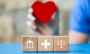 Trzy kostki z symbolami: budynek, krzyż, waga. W tle serce, symbolizujące wsparcie dla osób z niepełnosprawnością 05-r.