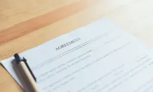 Dokument "Umowa" z długopisem na drewnianym tle.
