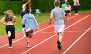 Dzieci biegnące po bieżni lekkoatletycznej podczas lekcji wychowania fizycznego.