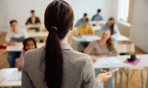 Nauczycielka z kucykiem prowadzi lekcję dla uczniów siedzących w ławkach.