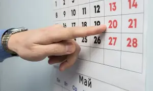 Palec wskazuje datę 20 na kalendarzu, symbolizującą okres wypowiedzenia umowy o pracę na czas nieokreślony.