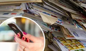 Stos listów i kopert, dłoń trzymająca smartfon.