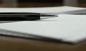 Czarny długopis leżący na białej kartce w linie.