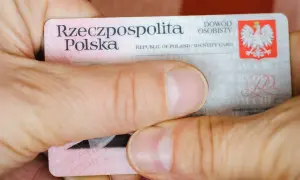 Dłonie trzymają polski dowód osobisty z widocznym godłem i napisem "Rzeczpospolita Polska".