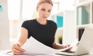 Kobieta analizuje dokumenty, być może dotyczące zakazu konkurencji po ustaniu stosunku pracy.