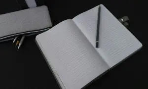 Otwarty zeszyt w linie, idealny do notatek z fizyki, obok piórnika z ołówkami.