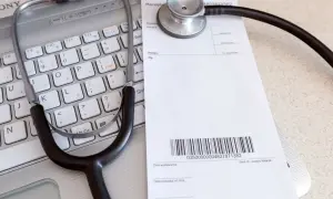 Stetoskop na klawiaturze laptopa obok recepty lekarskiej.