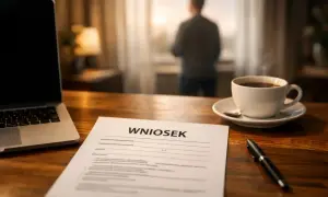 Na biurku leży wniosek, obok laptop i filiżanka kawy. Mężczyzna stoi przy oknie, rozważając pracę zdalną okazjonalną.
