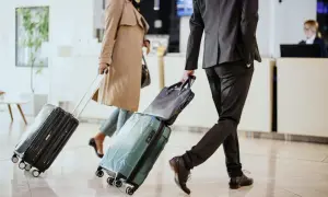 Biznesmeni z walizkami w hotelowym lobby, gotowi na polecenie wyjazdu służbowego.