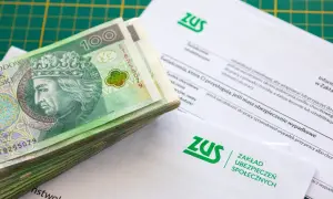Stos banknotów 100 zł na dokumentach ZUS.