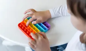 Dziecko bawi się tęczową zabawką sensoryczną typu pop it.