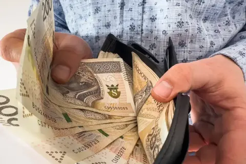 Dłonie trzymające portfel z polskimi banknotami 200 zł.