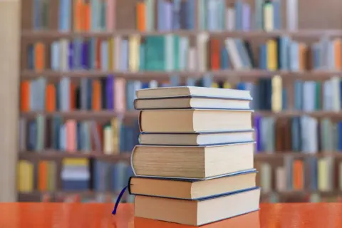 Stos książek na biurku, tło biblioteki z kolorowymi lekturami na e8.
