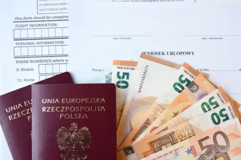 Paszporty i euro leżą obok wniosku urlopowego. Czy urlop okolicznościowy przepada, gdy brakuje środków na podróż?