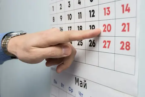 Palec wskazuje datę 20 na kalendarzu, symbolizującą okres wypowiedzenia umowy o pracę na czas nieokreślony.
