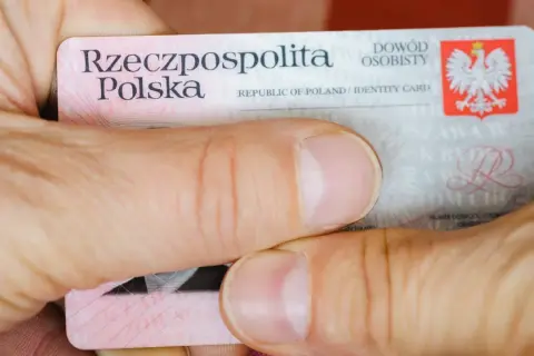 Dłonie trzymają polski dowód osobisty z widocznym godłem i napisem "Rzeczpospolita Polska".