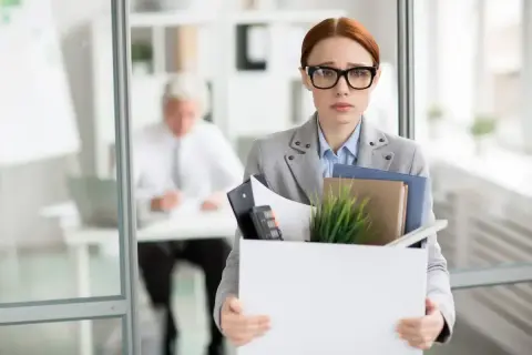 Smutna kobieta z pudełkiem rzeczy po likwidacji stanowiska pracy. Czy otrzyma należną odprawę?