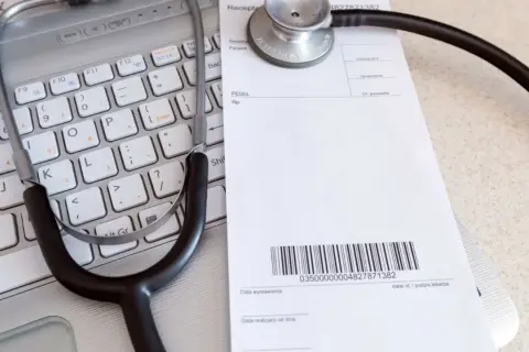 Stetoskop na klawiaturze laptopa obok recepty lekarskiej.