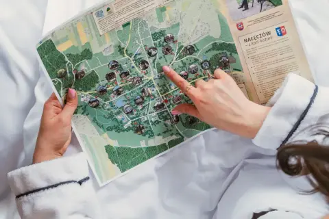 Dłoń wskazuje na mapę z zaznaczonymi atrakcjami turystycznymi.
