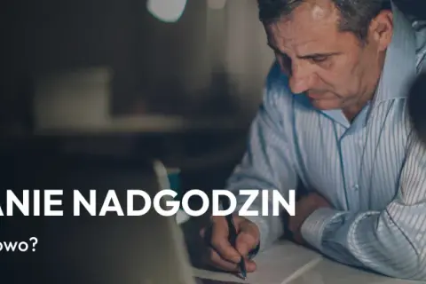 Mężczyzna pochyla się nad dokumentami, pisząc coś długopisem. Temat: rozliczanie nadgodzin, zgodnie z art. 151 kp.