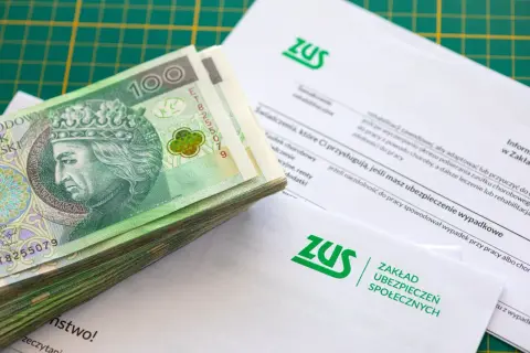 Stos banknotów 100 zł na dokumentach ZUS.