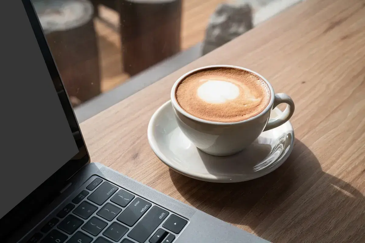 Kawa latte obok laptopa. Idealna przerwa na 8 godzin pracy, by naładować baterie.