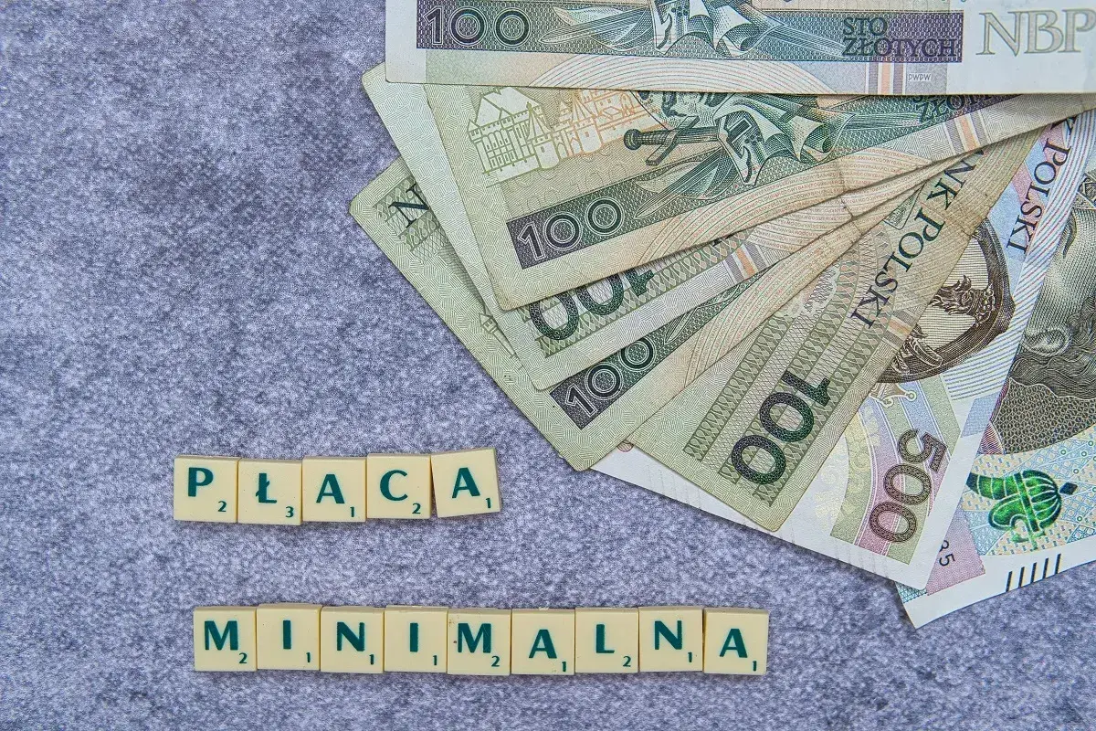 Płaca minimalna w Polsce to temat dyskusji. Na zdjęciu polskie banknoty i litery tworzące hasło.