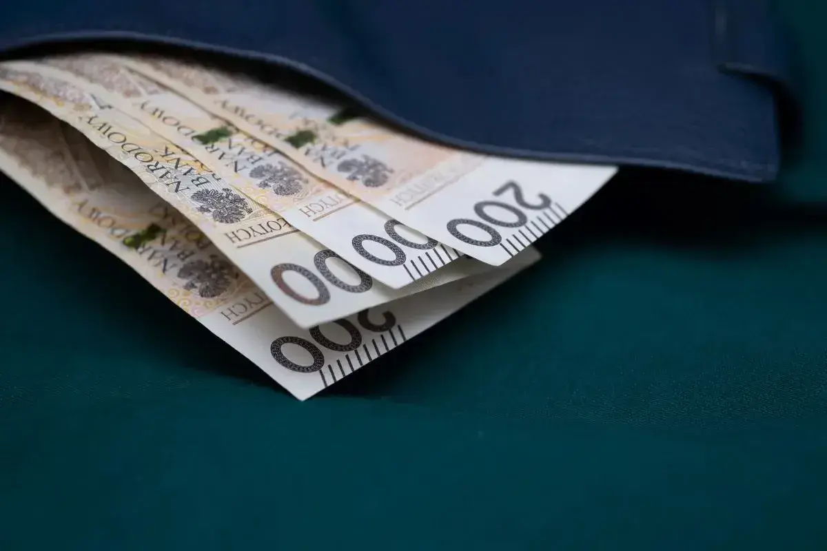 Złote banknoty 200 zł schowane w granatowym portfelu.