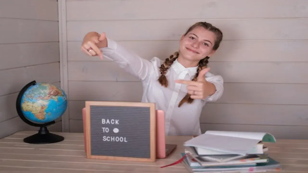 Uśmiechnięta dziewczyna z warkoczami wskazuje palcami na tabliczkę "Back to School" obok globusa i stosu książek.