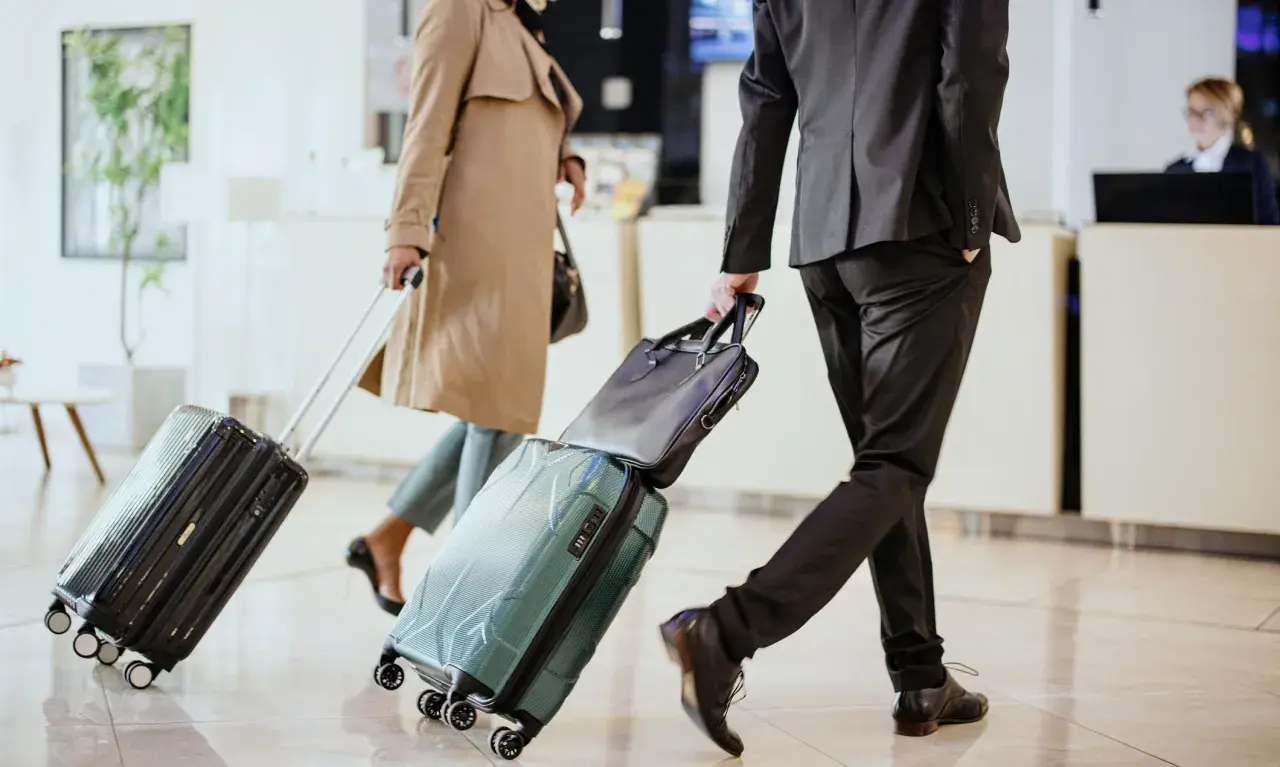 Biznesmeni z walizkami w hotelowym lobby, gotowi na polecenie wyjazdu służbowego.