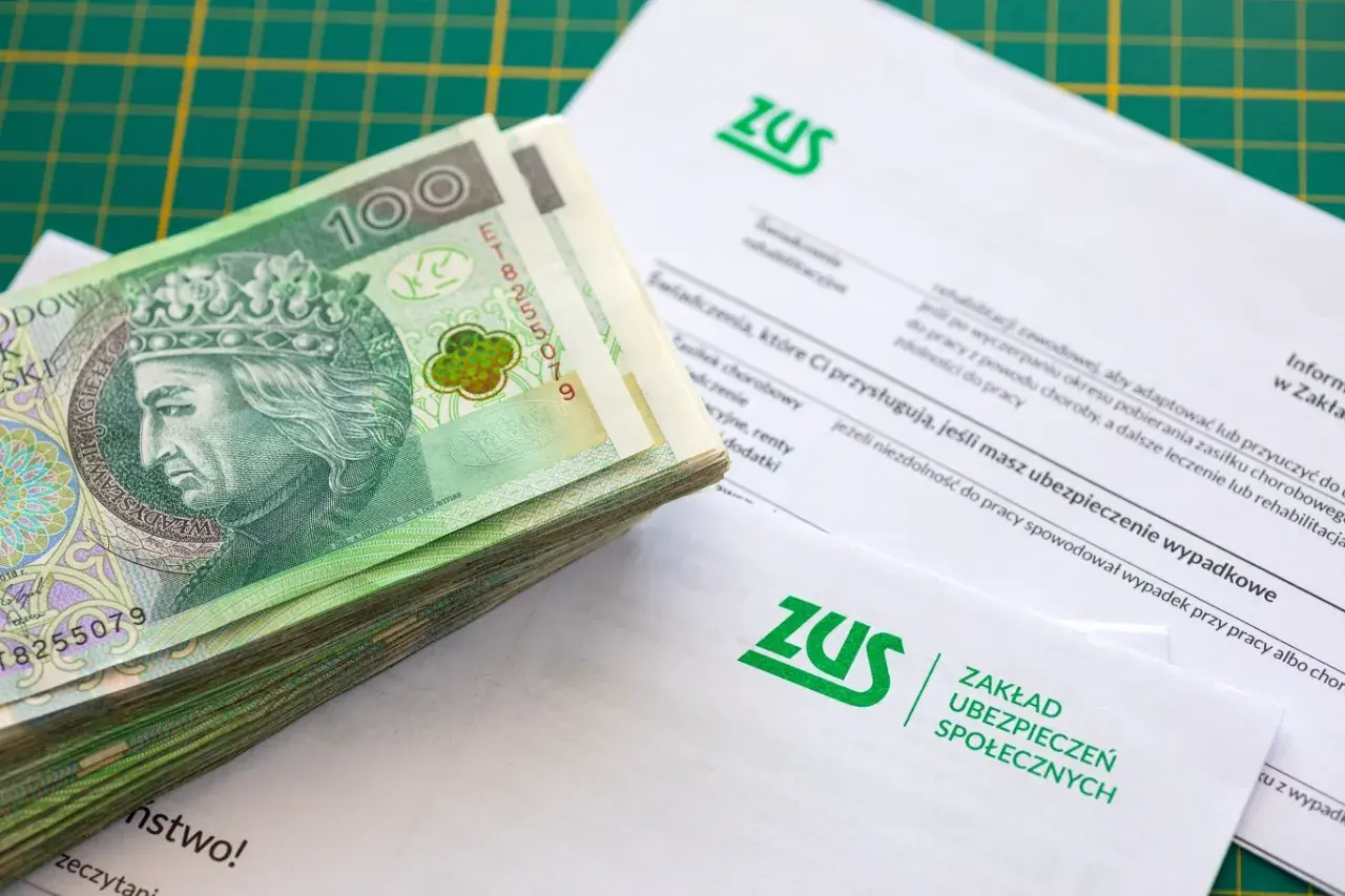 Stos banknotów 100 zł na dokumentach ZUS.