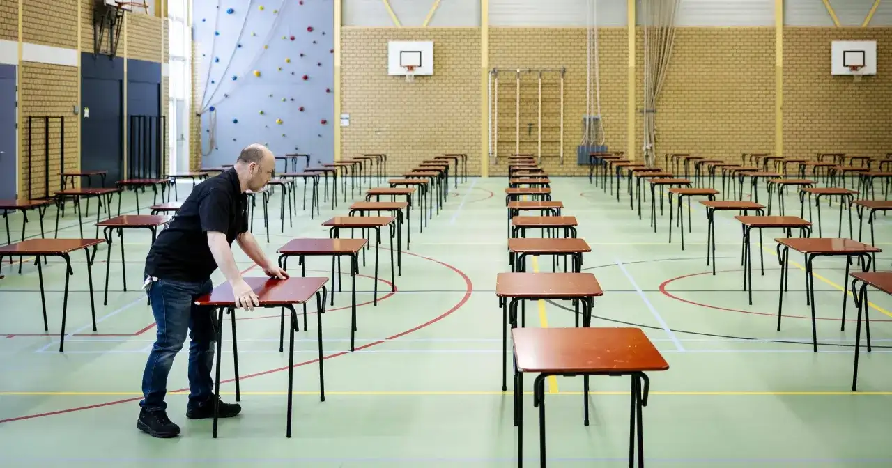 Mężczyzna ustawia ławki w sali gimnastycznej. Przygotowania do egzaminu ósmoklasisty, który trwa kilka godzin.