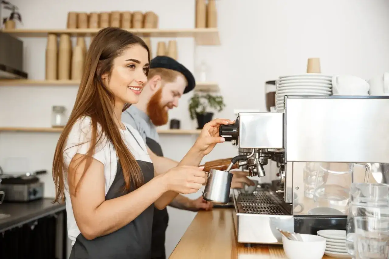Młoda barista przygotowuje kawę. Od ilu lat można pracować w kawiarni? Odpowiedź zależy od przepisów, ale ta dziewczyna wygląda na gotową do pracy!