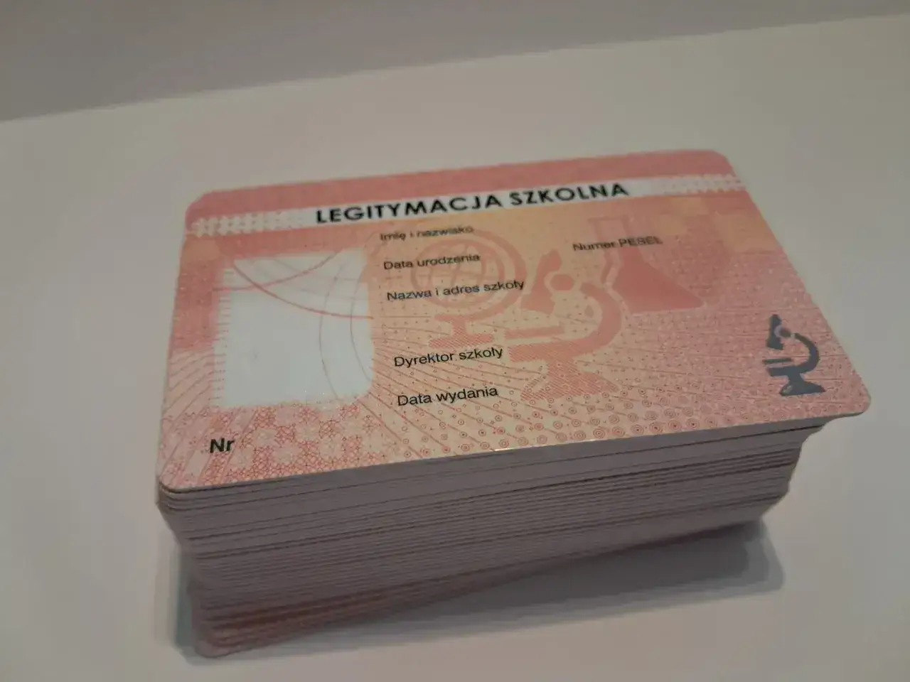 Stos legitymacji szkolnych. Na górnej widać pole na zdjęcie, imię, nazwisko, datę urodzenia, nazwę szkoły, numer PESEL, dyrektora, datę wydania i numer. Ile cyfr ma numer legitymacji szkolnej?
