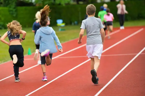 Dzieci biegnące po bieżni lekkoatletycznej podczas lekcji wychowania fizycznego.