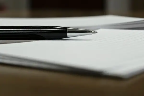 Czarny długopis leżący na białej kartce w linie.
